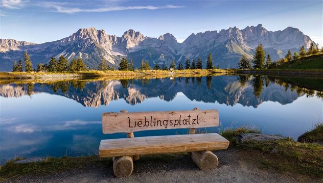 A tranquil landscape with a clear lake and majestic mountains in the background. A wooden bench with the inscription "Favorite Spot" invites you to linger.