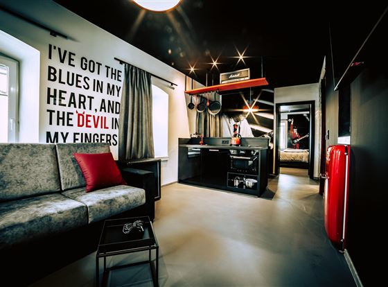 Ein modernes Zimmer mit einem Sofa und einer kleinen Küchenzeile. An der Wand steht ein kreativer Spruch in großen Buchstaben.