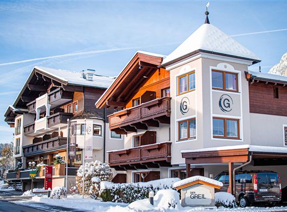Een aantrekkelijk hotelgebouw in de sneeuw, omgeven door een pittoresk winterlandschap. Helderblauwe luchten en met sneeuw bedekte daken zorgen voor een serene sfeer.