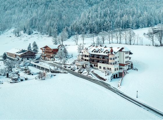 Eine malerische Winterlandschaft mit schneebedeckten Gebäuden. Die Umgebung ist ruhig und von Bergen umgeben.