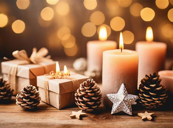 Eine festliche Dekoration mit Kerzen, Geschenken und Tannenzapfen. Im Hintergrund leuchten unscharfe Lichter und schaffen eine gemütliche Stimmung.