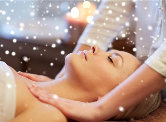Eine Frau erhält eine entspannende Massage. Sanfte Schneeflocken wirken beruhigend im Hintergrund.