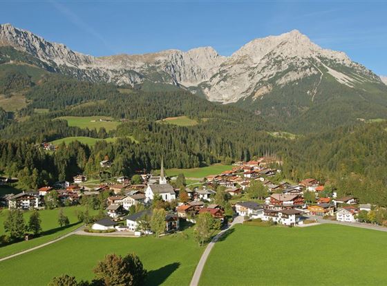 Eine malerische Berglandschaft mit einer kleinen Stadt im Tal. Die Umgebung ist grün und von majestätischen Bergen umgeben.