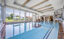 A stylish indoor pool with large windows and a view of the mountains. The water is clear and the architecture is modern and welcoming.