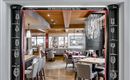 An elegant restaurant with modern furnishings and wooden decor. The entrance area is stylishly designed and conveys an inviting atmosphere.
