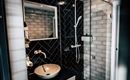 A modern bathroom with an elegant shower and a contemporary sink. The walls are decorated with black and white tiles.