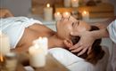 A relaxing wellness treatment with a woman receiving a head massage. The surroundings feature candles and a tranquil atmosphere.
