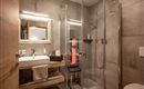 A modern bathroom with a glass shower and light wood details. The mirror and the sink faucet create a stylish atmosphere.
