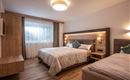 A modern hotel room with two beds and soft blankets. Large windows provide plenty of light and a pleasant atmosphere.