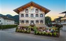 A charming restaurant with a blooming terrace and an inviting ambiance. The facade of the house is traditionally designed and surrounded by mountains.