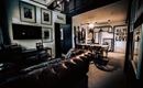 A modern living and working room with a cozy leather couch. On the wall, there are frames with pictures and an inspiring wall quote.