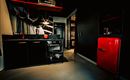 A modern kitchen with black furniture and a red refrigerator. The environment is stylish and well-furnished.