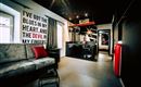 A modern room with a sofa and a small kitchenette. On the wall is a creative saying in large letters.