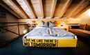 A modern bedroom with a large bed and wooden ceiling. The bed frame has the inscription "Love me like there’s no tomorrow."