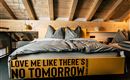 A modern bedroom with a striking bed and cozy bedding. The walls are made of wood, and the ceiling has exposed beams.