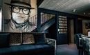 A modern living room with an artistic mural of a man. One wall features inspirational writings, while stylish furniture decorates the space.