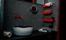 A modern bathroom with gray walls and red accents. In the foreground is a stylish sink and towels are neatly placed.