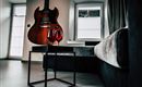 A modern living room with an electric guitar on the wall. On a table, there are two wine glasses.