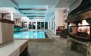 An elegant indoor pool with illuminated water and a cozy fireplace. The atmosphere is relaxing and inviting.