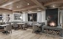 A cozy restaurant with wooden decor and elegant chairs. The fireplace creates a warm atmosphere.
