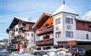 An attractive hotel building in the snow, surrounded by a picturesque winter landscape. Clear blue skies and snow-covered roofs create a serene atmosphere.