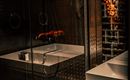 A modern bathroom with an elegant shower and a white bathtub. The walls are made of dark material, creating a stylish atmosphere.