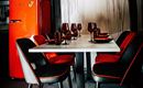 A stylish dining area with a white table, black and red chairs, and a striking red refrigerator in the background. Glassware and plates are beautifully set, adding a vibrant atmosphere to the space.