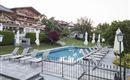 A beautiful outdoor area with a pool and loungers. The surroundings are green and well-maintained, perfect for relaxing.