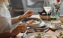An elegant breakfast with a plate that contains eggs and vegetables. Next to it is a glass of wine and a cup of coffee.