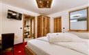 A modern bedroom with a large bed and wooden furniture. The room has a television and a pleasant atmosphere.
