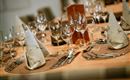 An elegantly set table with cutlery, glasses, and decorated napkins. The warm wood look creates an inviting atmosphere.