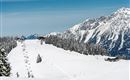 A dreamy winter landscape with snow-covered mountains and a ski resort. The surroundings are calm and inviting for winter sports enthusiasts.