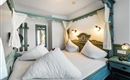 A cozy bedroom with a large bed and three decorative pillows. The beautiful walls and warm lights create an inviting atmosphere.