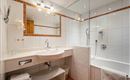 A modern bathroom with a shower and a bathtub. The white tiles and the good lighting create a bright atmosphere.