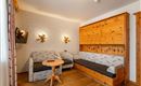 A cozy living room with wood paneling and a sofa. A round table and a television are also present.