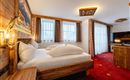 A cozy bedroom with wooden paneling and two beds.  

Large windows provide plenty of daylight, and a modern TV corner is also available.