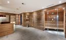 A modern wellness area with wooden walls and soft lighting. The sauna and reception areas are designed to be clear and inviting.