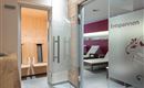 A modern wellness area with glass doors. On the left side, there is a sauna, while the room on the right invites you to relax.