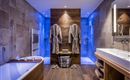 A modern bathroom with a bathtub and elegant wood paneling. Two bathrobes hang next to a sink with soft lighting.