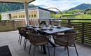 A tastefully furnished dining table on a terrace with a view of green hills and mountains. The space is bright and inviting, perfect for sociable meals outdoors.
