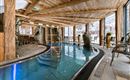 An elegant indoor pool in a wooden-decorated room. The light gently falls through the windows, creating a relaxing atmosphere.