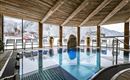 An indoor pool in a wooden cabin with large windows overlooking snow-covered mountains. Relaxation and tranquility in a cozy atmosphere.