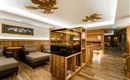 A cozy room with wooden furniture and a central aquarium. Ceiling decorations and warm lighting create an inviting atmosphere.