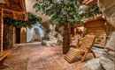 A relaxing wellness area with wooden furniture and artificial trees. Gentle lighting creates a calm atmosphere.