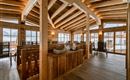 A cozy restaurant with wooden ceilings and large windows. The decor is rustic and inviting.
