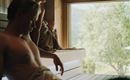 Two people are relaxing in a sauna. The room is made of wood and offers a view of the nature outside.