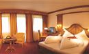 A cozy hotel room with a large bed and colorful curtains. There is a seating area with a table and a television in the room.