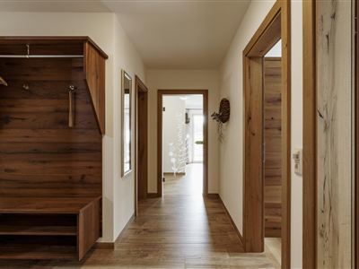 A bright hallway with wooden shelves and doors. The floor is made of wood, and the room feels friendly and inviting.
