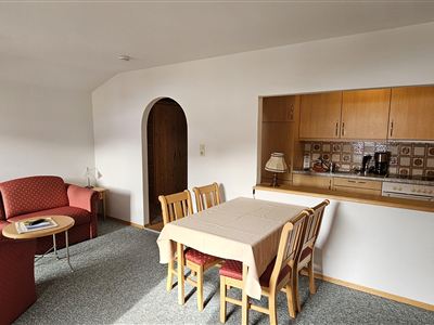 Ein gemütlicher Wohnbereich mit rotem Sofa und Esstisch. Die offene Küche ist in den Raum integriert.