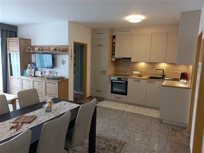 Eine moderne Küche mit hellen Schränken und Geräten. Der Essbereich ist gemütlich mit einem großen Tisch und Stühlen.